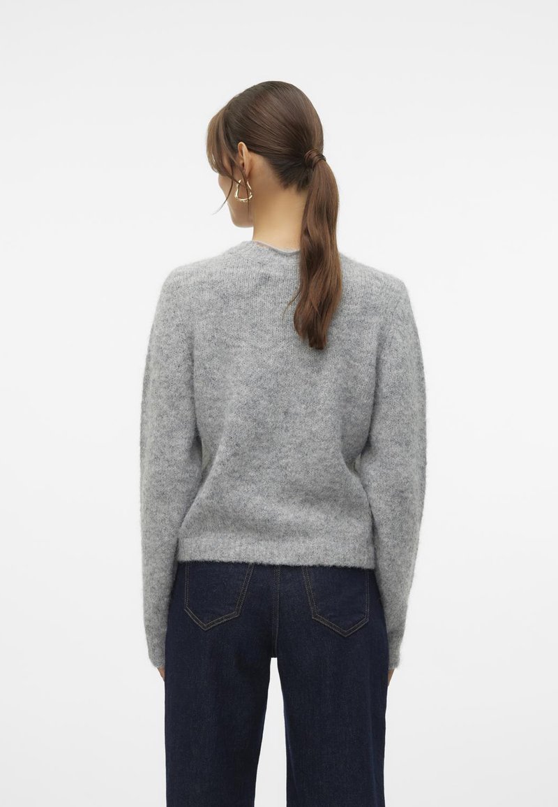 Grau, flauschiger Strickpullover mit rundem Ausschnitt, langen Ärmeln und ribbeligem Saum. Getragen mit dunkelblauen Jeans, die die Rückenansicht zeigen.