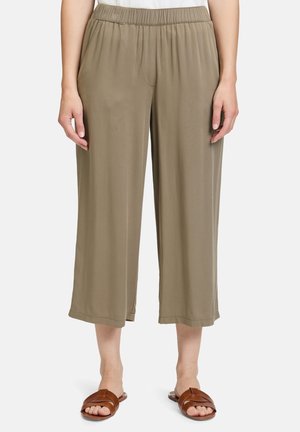 Khaki Culottes mit einem weiten Bein Design, elastischem Bund, weichem Stoff und seitlichen Taschen, kombiniert mit braunen Riemchensandalen.