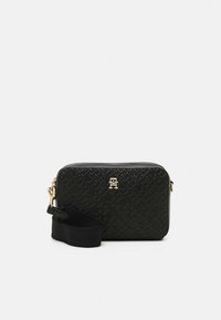 Black crossbody bag made of textured synthetic material, featuring an embossed pattern, gold hardware, and a black strap.