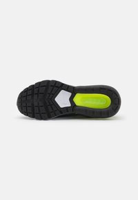 Suela de zapato atlético negra con goma texturizada, tecnología de amortiguación verde lima y un detalle de soporte hexagonal gris en contraste.