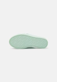 Suola di scarpa verde chiaro con un motivo testurizzato caratterizzato da forme geometriche e una forma leggermente curva, realizzata in materiale gommoso resistente.
