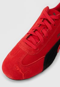 Κόκκινο σουέτ αθλητικό παπούτσι Puma με μαύρη σόλα, κόκκινες κορδόνες και κεντημένο λογότυπο Puma στο δάκτυλο και στο πλάι.