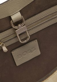 Borsa a mano in pelle beige e marrone, con cerniera frontale, ferrature argento e finitura testurizzata con dettaglio del logo in rilievo.