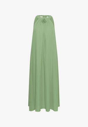 Robe longue fluide vert pâle avec col halter et une fleur décorative au niveau de l'encolure.