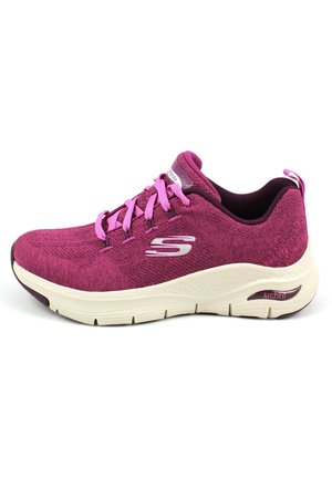 Zapatilla de punto morada con cordones rosas, suela crema acolchada y detalle de logo en el lateral. Presenta un tejido texturizado y un diseño que brinda soporte.