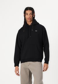Schwarzer Hoodie aus weichem Material, mit einer Kängurutasche, verstellbarem Kapuzenzug und kleinem weißem Logo auf der Brust. Klassische Passform.