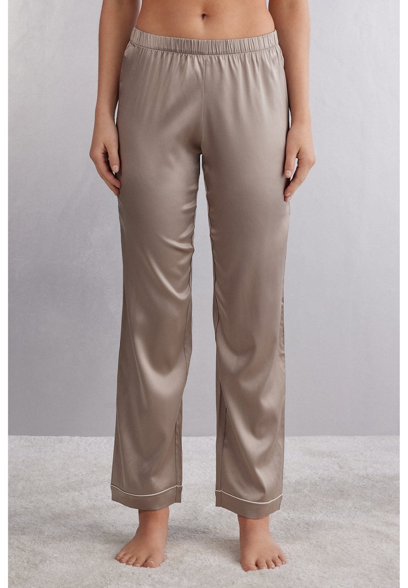 Satin pyjamabroek in een zachte beige kleur met een elastische tailleband en witte bies langs de zomen. Glad textuur, recht gesneden ontwerp.