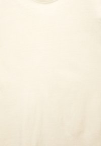 Lichtbeige T-shirt met ronde hals, gemaakt van zachte, gladde stof; heeft een eenvoudig, effen ontwerp zonder patronen of accenten.