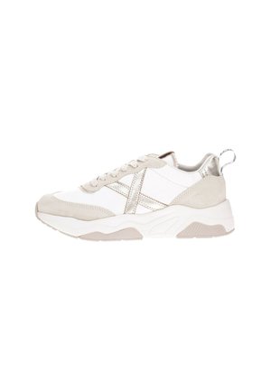 Sneaker bianco e grigio chiaro con materiali in suede e mesh, caratterizzato da accenti metallici, suola testurizzata e lacci decorativi.