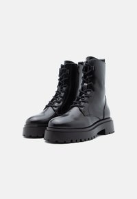 Botas de combate pretas em couro com sola grossa, apresentando atacadores e um fecho lateral em zíper. Acabamento liso com textura durável e piso resistente.