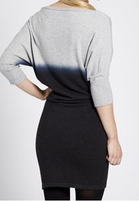 Grau- und schwarz gemustertes Strickkleid mit Dreiviertelärmeln, das eine lockere Passform und gerippte Details am Ausschnitt und Saum aufweist.