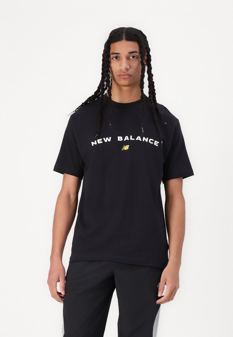 Melna kokvilnas T krekls ar īsām piedurknēm, ar uzrakstu "NEW BALANCE" baltā krāsā un zelta logotipu centrā. Gluda tekstūra.