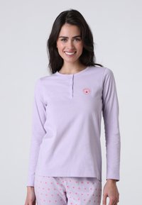 Maglietta a maniche lunghe viola con colletto a bottoni, caratterizzata da una piccola grafica di fiore arancione. La maglietta ha una texture liscia ed è abbinata a pantaloni a fantasia.