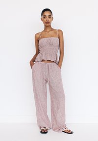 Set med lättviktig, rosa randig ärmlös topp och vida byxor. Toppen har elastiskt veck, byxorna har dragsko i midjan och fickor.
