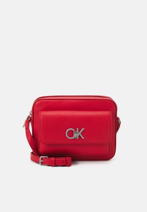 Red rectangular crossbody bag with front pocket flap and silver "ck" logo, featuring adjustable strap and zipper closure.