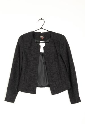 Schwarzer strukturierter Damenblazer mit langen Ärmeln und offenem Vorderteil, hängend an einem schwarzen Bügel vor weißem Hintergrund.