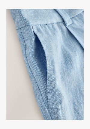 Hellblauer Stoff mit Fischgrätenmuster, der eine weiche Textur und plissierte Design-Details aufweist. Beinhaltet eine Seitentasche und saubere Nähte.