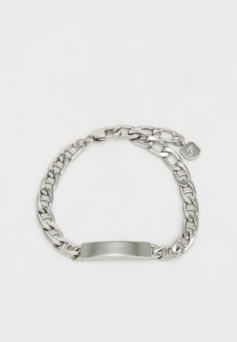 Pulseira de metal prateado com elos de corrente entrelaçados, uma chapa central lisa e uma pequena etiqueta de marca. Design durável e elegante.