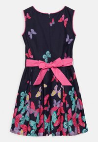Tmavě modré bavlněné šaty s motýlími vzory v růžové, červené, fialové a tyrkysové barvě; mají růžovou mašli v pase a zapínání na zip na zádech.