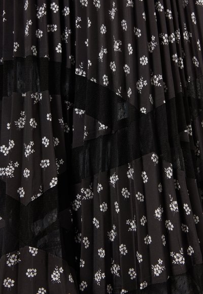 Vestido negro con pliegues y patrón floral blanco, que presenta secciones de tela transparente y sólida. Superficie texturizada con patrones contrastantes.