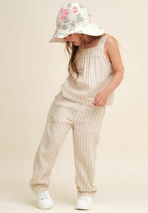 Beige og hvid stribet tanktop og bukser i let stof, parret med en blomstermønstret bøttehat og hvide sneakers.