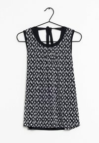 Haut sans manches noir et blanc avec motif en losange, tissu lisse, encolure arrondie et détail noué à l'arrière. Suspendu à un crochet noir.