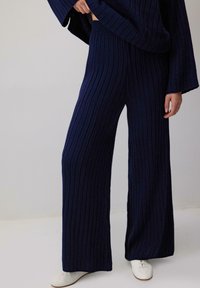 Merine ribaga kootud vabaaja komplekt, mis sisaldab laia jala pükse ja laia lõikega toppi, millel on tekstureeritud viimistlus ja elastne vöökoht.