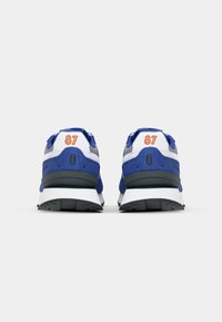 Blue and white athletic sneakers with a cushioned sole, featuring a textured upper and bold orange "87" detail on the heel.