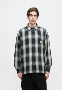 Mėlynos ir smėlio spalvos languota marškinė su mygtukais; ilgos rankovės, laisvas kirpimas, pagaminti iš minkštos medžiagos; turi krūtinės kišenę su logotipu.