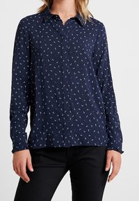Camicia button-up blu navy con un piccolo motivo a ancora. Presenta un colletto e maniche lunghe con polsini elastici. Tessuto morbido.