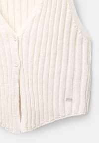 Strick ärmellose Cardigan in Off-White, mit vertikalen Rippen, einem V-Ausschnitt und zwei vorderen Knöpfen. Enthält einen kleinen metallischen Logo-Akzent.