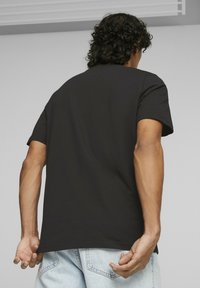 Czarna bawełniana koszulka z krótkim rękawem, luźny fason i okrągły dekolt, w połączeniu z jasnoniebieskimi dżinsami.