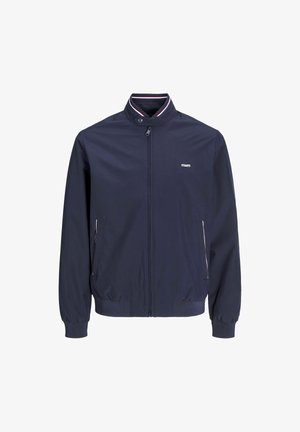 Tamsiai mėlynas lengvas švarkas su aukštu apykakle, užtrauktuku ir raukšlėtais rankogaliais. Yra šoninės kišenės su kontrastingu apdailu ir logotipo detale.