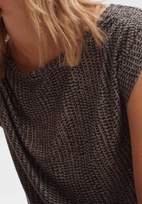 Kortärmad topp med ett texturerat mönster i mörkbrun och beige. Det släta tyget faller mjukt med en rund halsringning.