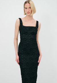 Schwarzes Spitzenkleid mit quadratischem Ausschnitt, figurnahem Schnitt, floralem Texturdetail und breiten Trägern. Ideal für Abendveranstaltungen.