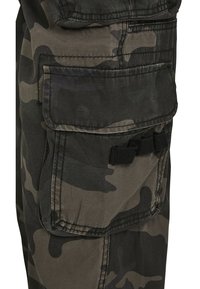 Pantalones cargo de camuflaje en tonos de verde y negro, con múltiples bolsillos, tejido texturizado y un detalle de costura reforzada.