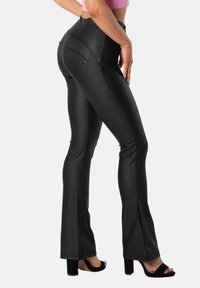 Musta korkea vyötäröinen levenevät housut, jotka on valmistettu sileästä, joustavasta materiaalista ja joissa on takataskut sekä hillityt ompelut.