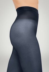Collant neri con vita alta, texture liscia e finitura semi-trasparente. Presentano una silhouette aderente e una parte superiore elasticizzata per il supporto.