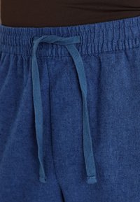 Marinenblå sweatpants med tekstureret stof, der har en elastisk talje og en matchende snor til justering.
