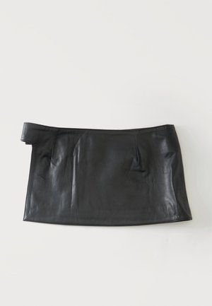 Mini-jupe en cuir noir avec un détail asymétrique à la taille sur fond blanc.