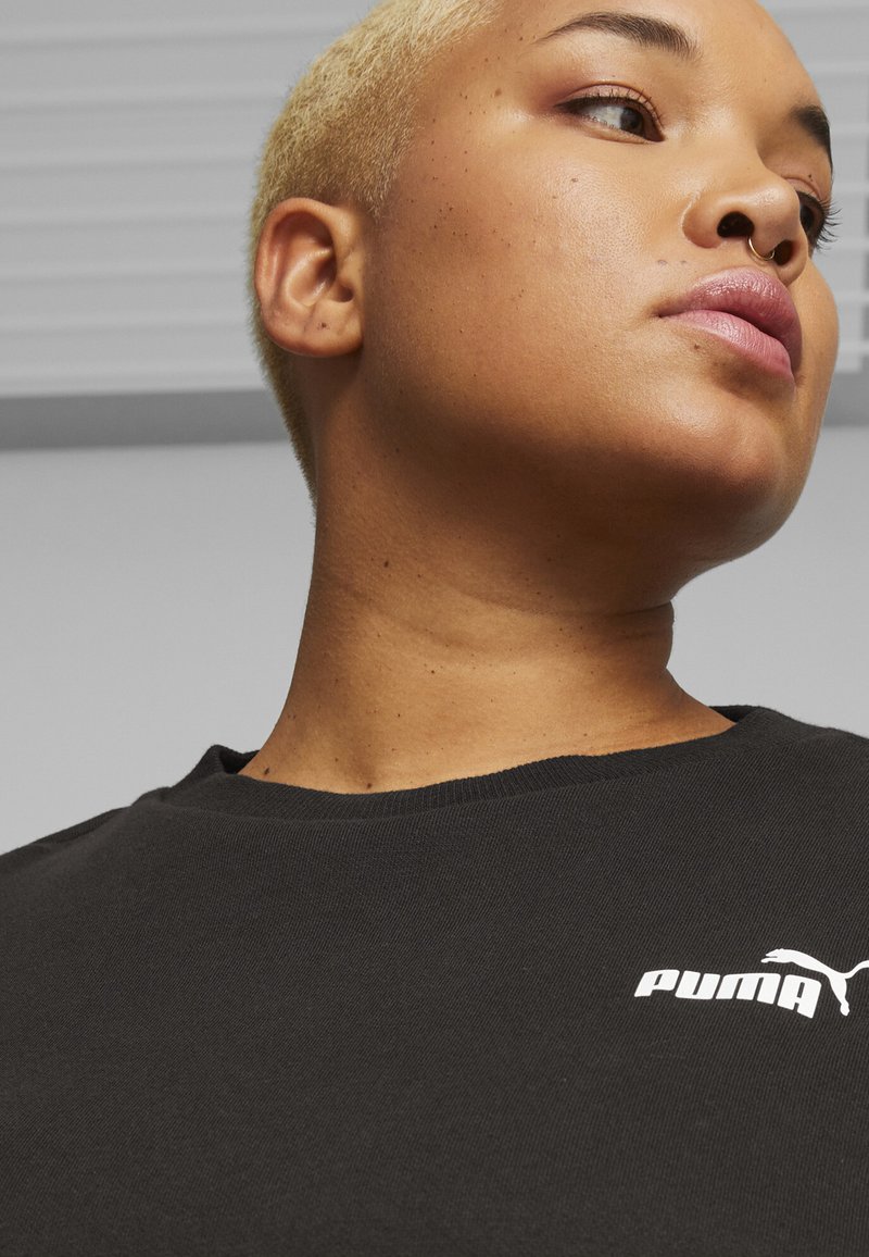 T-shirt in cotone nero con scollatura rotonda e maniche corte, caratterizzato da un logo Puma bianco sul lato sinistro e una texture liscia.