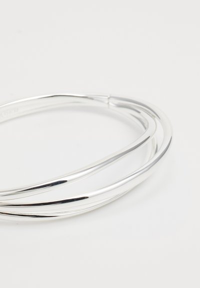 Bracelet en argent présentant trois brins entrelacés, texture lisse et finition polie, mettant en valeur un design élégant et contemporain.