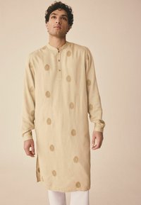 Beiger Kurta mit langen Ärmeln, Knopfleiste und goldenen Blattmustern throughout. Seitenschlitze verbessern die Beweglichkeit. Glatte Stoffoberfläche.