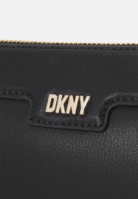 Fekete bőr tárca, texturált felülettel. Aranyozott, dombornyomott "DKNY" logóval és arany cipzárral a tetején.