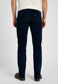 Pantaloni in velluto a coste blu marino con taglio dritto, dotati di tasche posteriori, un tessuto testurizzato e una toppa in pelle in vita.