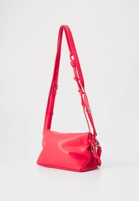 Borsa a spalla rossa in finta pelle con tracolla regolabile, forma rettangolare, texture liscia e un dettaglio annodato sulla tracolla.