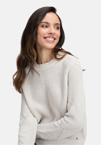 Helle graue Strickjacke mit einer strukturierten, groben Webart. Besitzt einen weiten Rundhalsausschnitt und dezente Nahtdetails an den Ärmeln.