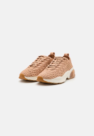 Woven-Pink-Sneaker mit strukturiertem Obermaterial, runder Zehenform und kontrastierender weißer Mittelsohle mit durchsichtiger Ferse.