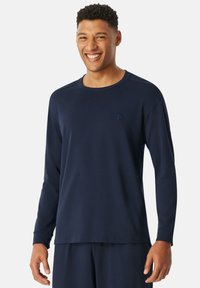 Navyblaues Langarmshirt aus weichem Stoff, mit rundem Hals, gesticktem Logo auf der Brust und gerippten Bündchen. Regelmäßige Passform.