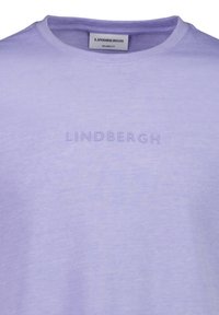 Lila T-shirt tillverkad av mjukt tyg, med en avslappnad passform och präglad "LINDBERGH"-logotyp på framsidan. Rund krage.